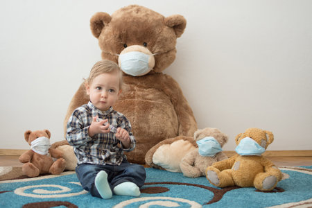 Child playing with his sick teddy bears wearing medical mask against viruses. Role playing, child playing doctor with plush toy. Children and flu, coronavirus illness concept. Selective focusの写真素材