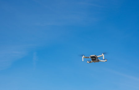 White drone with photo camera flying in the blue skyの写真素材