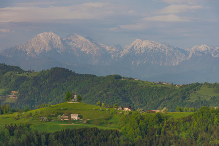 Slovenian breathtaking landscape with Julian Alps and charming little church of Sveti Tomaz (Saint Thomas) on a hill. Beautiful spring in the mountains, in Slovenia.の写真素材