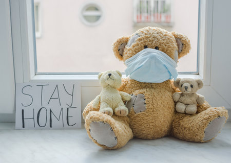 Sick teddy bear family in home quarantine wearing a medical mask against viruses during coronavirus COVID-19 and flu outbreak, with the advice to stay home.の写真素材