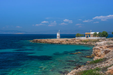 The wild coast of Aegina island with clear and blue waters of Mediterranean sea and the old small lighthouse in the background, in Saronic gulf, Greece.の写真素材