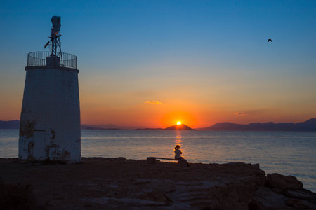 Old small lighthouse of the Aegina island, Saronic gulf, Greece, at sunset.の写真素材