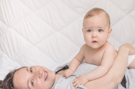 Happy mother playing with sweet little baby boy, white backgroundの写真素材