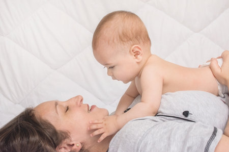 Happy mother playing with sweet little baby boy, white backgroundの写真素材