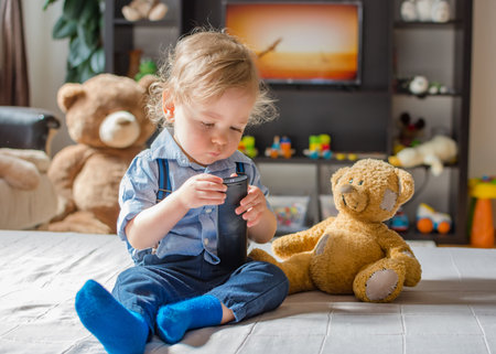 Cute baby boy playing with the remote control on a couch in the living room at homeの写真素材