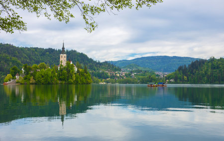 Beautiful morning at Lake Bled and Julian Alps in the background. The lake island and charming little church dedicated to the Assumption of Mary are famous tourist attraction in Sloveniaの写真素材