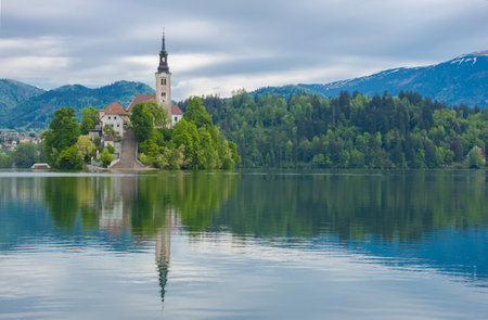 Beautiful morning at Lake Bled and Julian Alps in the background. The lake island and charming little church dedicated to the Assumption of Mary are famous tourist attraction in Sloveniaの写真素材