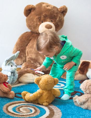 Cute child having fun playing with his teddy bears and plush toys, at homeの写真素材