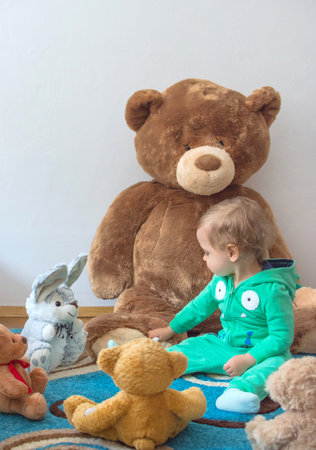 Cute child having fun playing with his teddy bears and plush toys, at homeの写真素材