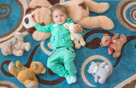 Cute child having fun playing with his teddy bears and plush toys, at home. Top viewの写真素材