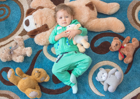 Cute child having fun playing with his teddy bears and plush toys, at home. Top viewの写真素材