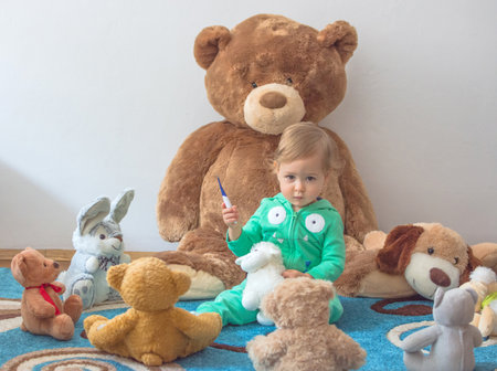 Cute child having fun playing with his teddy bears and plush toys, at homeの写真素材