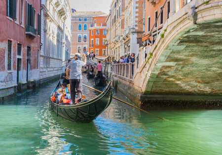 Venice, Italy - April 20, 2019: Venetian canal with gondolas and historic houses, in a beautiful sunny day.の写真素材