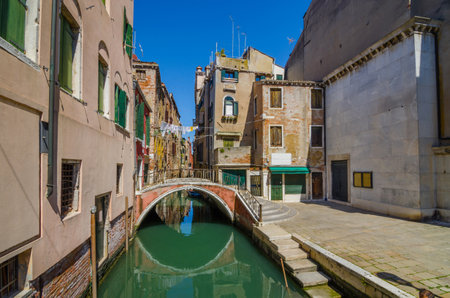 Narrow canal in Venice, Italy, with boats and historic houses, in a beautiful sunny day.の写真素材