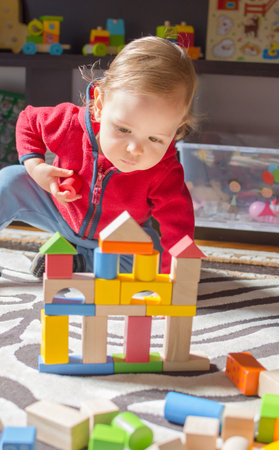 Cute child having fun playing with colorful wooden blocks, at home.の写真素材