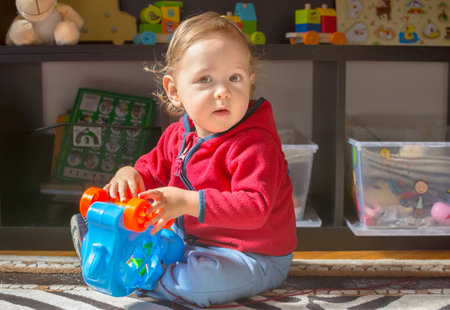 Happy sweet baby boy having fun playing with colorful toys, at homeの写真素材