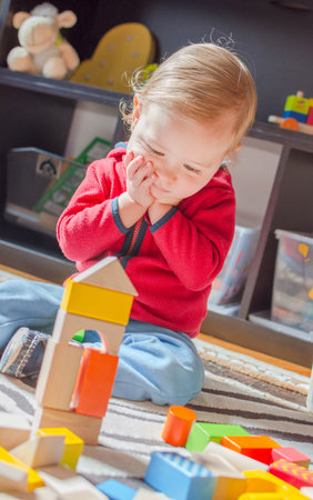 Cute child having fun playing with colorful wooden blocks, at home.の写真素材