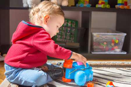Happy sweet baby boy having fun playing with colorful toys, at homeの写真素材