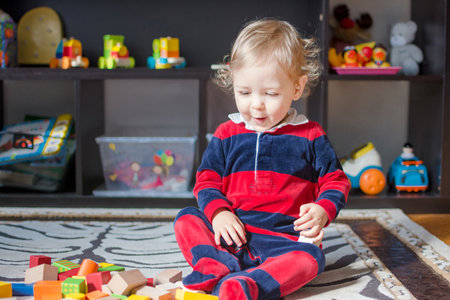 Cute little baby boy having fun at home playing with colorful wooden blocks, on the floor.の写真素材