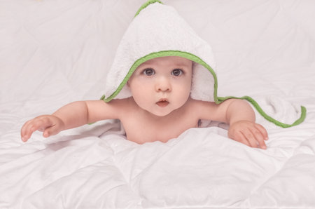 Sweet little baby boy portrait with towel on his head, on white backgroundの写真素材