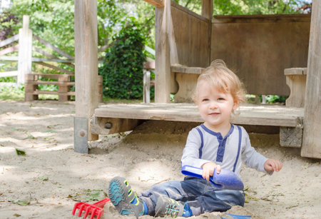 Cute little child having fun playing with sand and colorful toys in the park, beautiful summer sunny day in children playgroundの写真素材