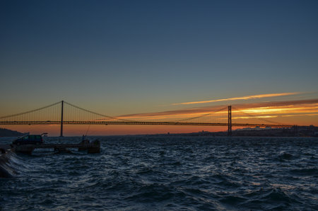 The 25th of April suspension bridge over the Tagus river, at sunset, in Lisbon, Portugal.