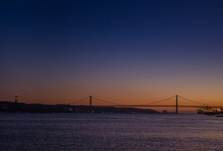 The 25th of April suspension bridge over the Tagus river, at sunset, in Lisbon, Portugal.の写真素材