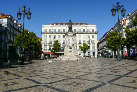 Camoes square with typical portuguese cobblestone hand-made mosaic pavement and monumental statue of 16th century epic poet Luis de Camoes standing on a pedestal, in Lisbon, Portugalの写真素材