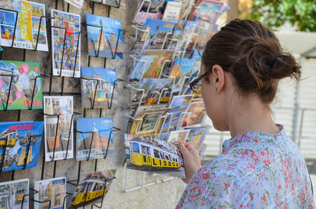 Lisbon, Portugal - 22 august 2018: Girl looking at colorful postcards in Lisbon