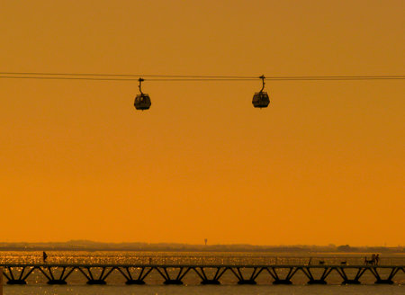 Telecabines (cable cars) at sunrise and people walking by the Tagus river at Park of Nations (Parque das Nacoes), in Lisbon, Portugal.の写真素材