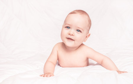 Sweet little baby boy sitting on his tummy, white backgroundの写真素材