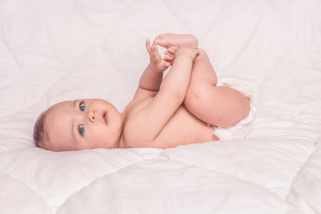 Sweet little baby boy sitting on his tummy, white backgroundの写真素材