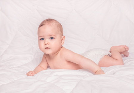 Sweet little baby boy sitting on his tummy, white backgroundの写真素材
