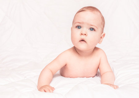 Sweet little baby boy sitting on his tummy, white backgroundの写真素材