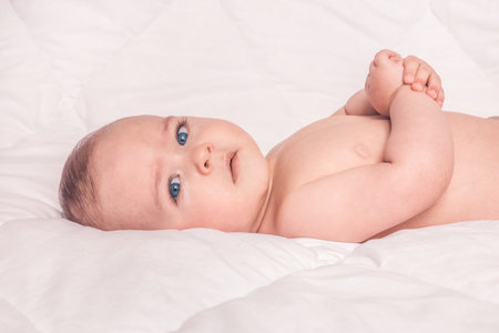 Sweet little baby boy sitting on his tummy, white backgroundの写真素材