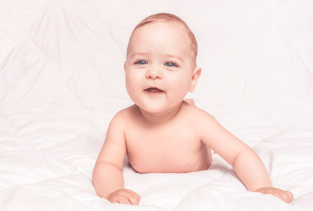 Sweet little baby boy sitting on his tummy, white backgroundの写真素材