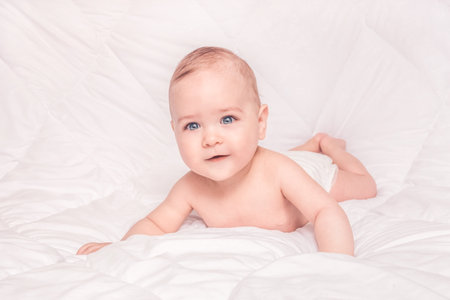 Sweet little baby boy sitting on his tummy, white backgroundの写真素材