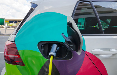 Modern electric car plugged in charging on the street station. New energy vehicles, environment friendly alternative energy for carsの写真素材