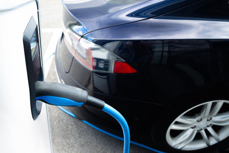 Man plugging in an electric car on the street station. New energy vehicles, environment friendly...