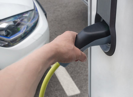 Man plugging in an electric car on the street station. New energy vehicles, environment friendly alternative energy for carsの写真素材