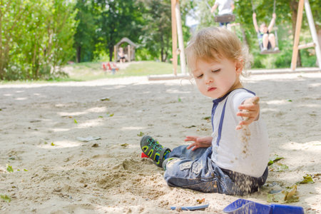 Cute little child standing on the grass in the parkの写真素材