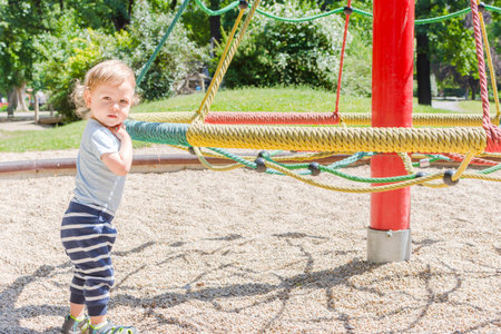 Cute little child standing on the grass in the parkの写真素材