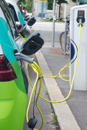 Modern electric car plugged in charging on the street station. New energy vehicles, environment friendly alternative energy for carsの写真素材