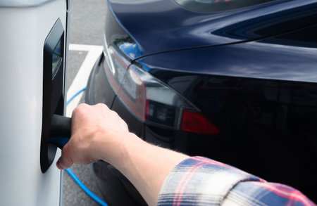 Modern electric car plugged in charging on the street station. New energy vehicles, environment friendly alternative energy for carsの写真素材