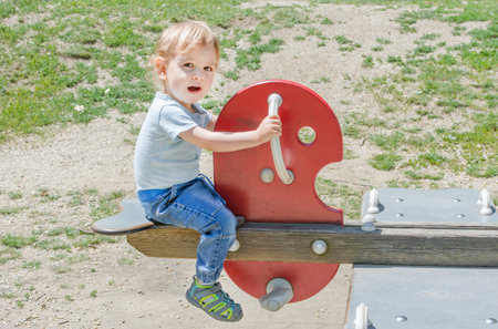 Funny baby child getting messy eating cereals or porridge by itself with a wooden spoon, straight from the cooking potの写真素材