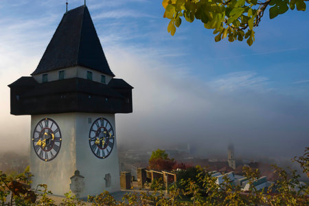 Cityscape of Graz with Church of the Sacred Heart of Jesus and historic buildings, in Graz, Styria region, Austria, at sunrise. Beautiful foggy morning over the city of Graz, in autumnの写真素材