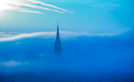 The famous clock tower on Schlossberg hill, in Graz, Styria region, Austria, at sunrise. Beautiful foggy morning over the city of Graz, in autumnの写真素材