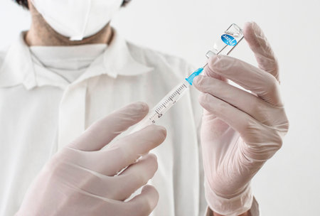 Graz,Austria-26.01.2021: Doctor holding a vaccine bottle and syringe, beginning of mass vaccination with the Pfizer-BioNTech COVID-19 vaccine, coronavirus world immunization conceptのeditorial素材