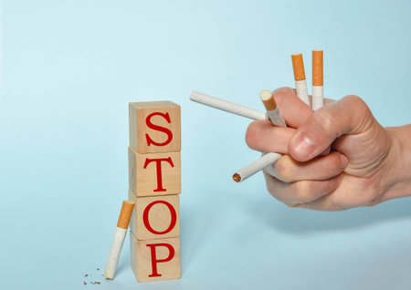 Stop smoking concept, hand holding many cigarettes and STOP text on wooden blocks. World No Tobacco Day on May 31 concept. Selective focusの写真素材