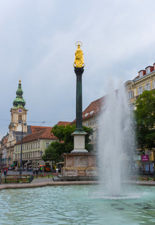 Graz/Austria - June 22, 2019: Mary's Column in Jakominiplatz Square and Parish Church (Stadtpfarrkirche) in the background, in the city center of Graz, Styria region, Austria.のeditorial素材